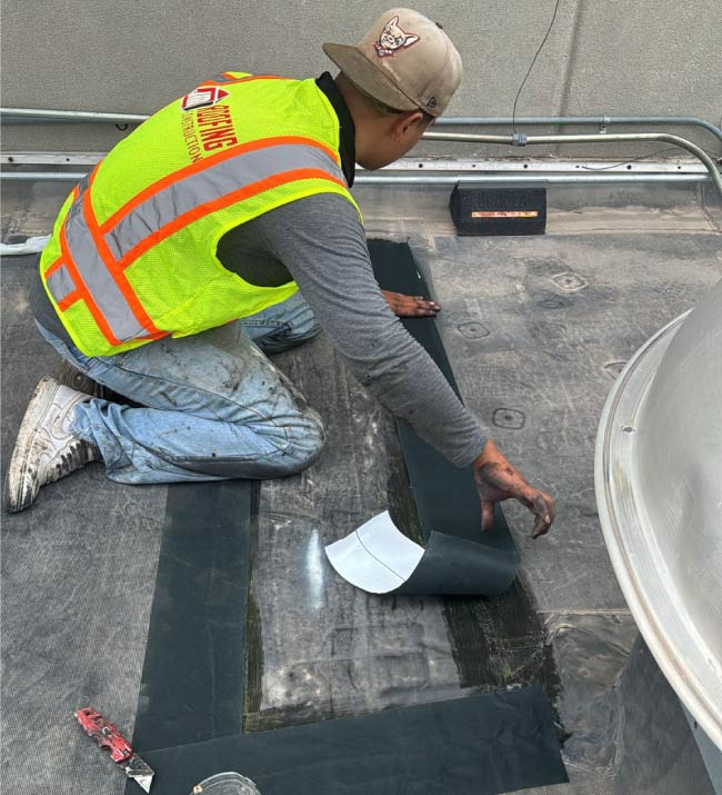 a professional roofer applying a protective coating to a commercial flat roof for extended lifespan in fabens, tx