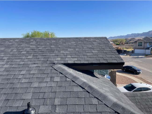 Freshly installed gray asphalt shingle roof replacement by JM Roofing with ridge cap detail, showing the quality work approved by homeowners insurance.