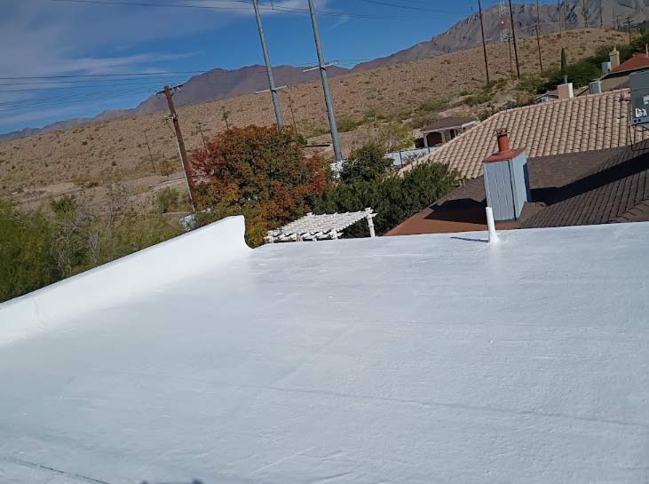 Finished white roof coating on a residential property with a parapet wall, providing a high-resistance, low-cost alternative to a full roof replacement.