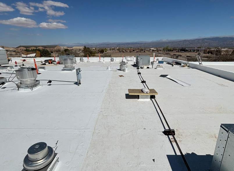 Expansive commercial TPO roof with a white reflective coating, highlighting professional installation around vents and rooftop equipment for maximum energy efficiency.