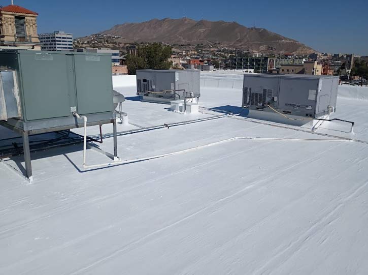 Roofer preparing a residential flat roof in El Paso, ensuring the surface is clear and ready for a protective coating to increase property value.