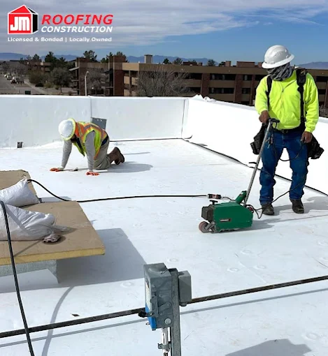A wide-angle view of a completed white TPO flat roof installation in El Paso, featuring a clean, reflective membrane surface and industrial ventilation equipment against a mountain backdrop.