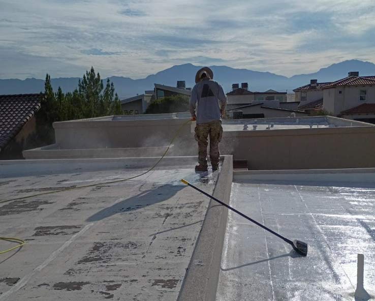Roofer preparing a residential flat roof in El Paso, ensuring the surface is clear and ready for a protective coating to increase property value.