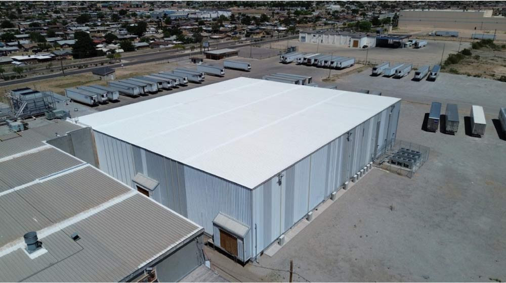JM Roofing crew applying a commercial roof coating system to a large warehouse in Socorro, TX.
