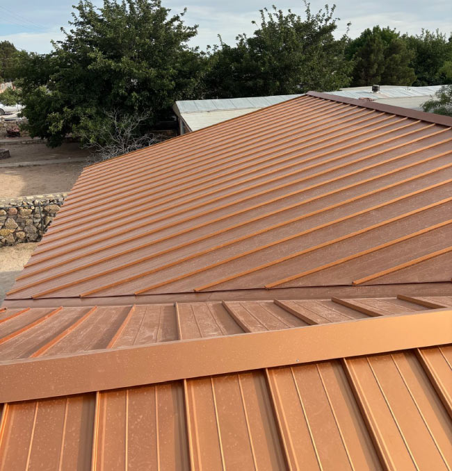 Professional metal roof installers completing a residential standing seam metal roof project in El Paso.