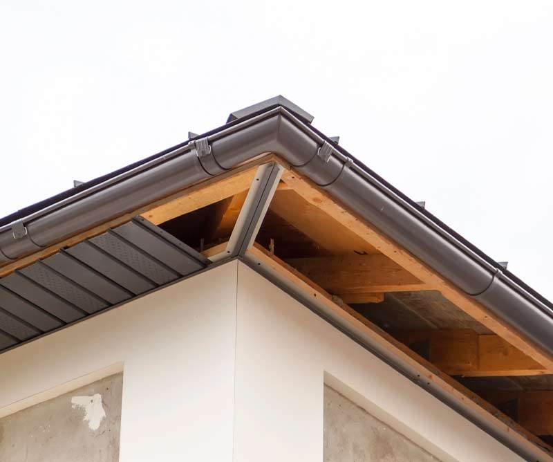 Close-up of a newly installed dark gray K-style gutter system along the corner eaves of a home.